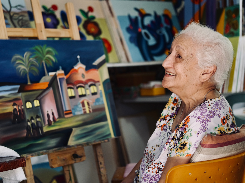 imagem de uma mulher idosa sorrindo em um laboratorio de artes